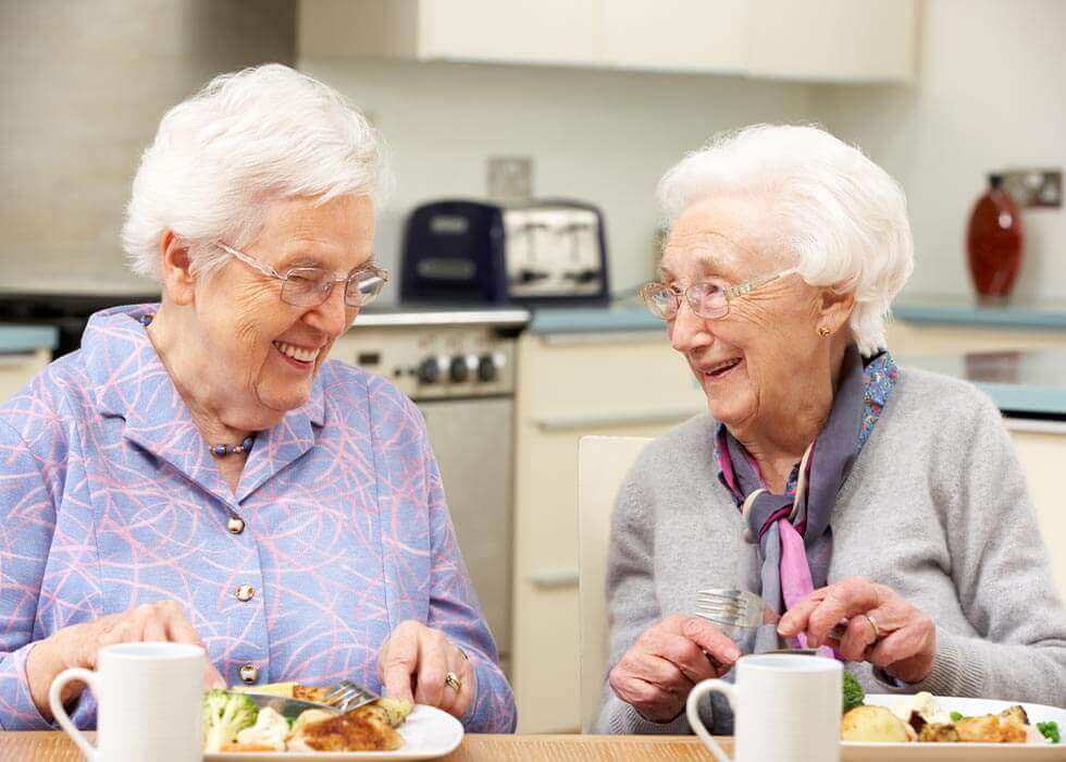 2 ältere Damen essen zusammen Mittag und unterhalten sich